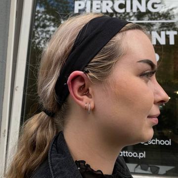 Výrazný piercing chrupavky propojující dvě místa jedním šperkem