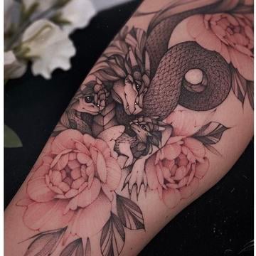 Blackwork tetování draka propleteného s pivoňkami na předloktí; 