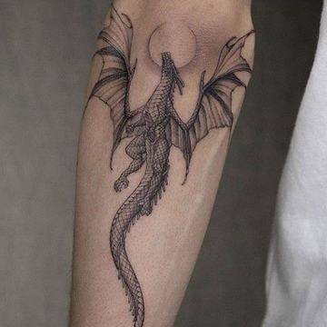 tetování draka s roztaženými křídly a dlouhým ocasem na vnitřním předloktí; 