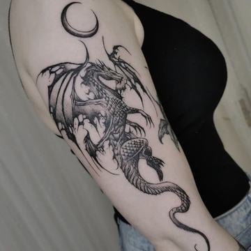 Blackwork tetování evropského draka s roztaženými křídly a detailními šupinami na horní části paže; 