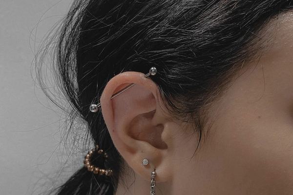 Piercing horní části ucha s individuálně navrženým vedením činky