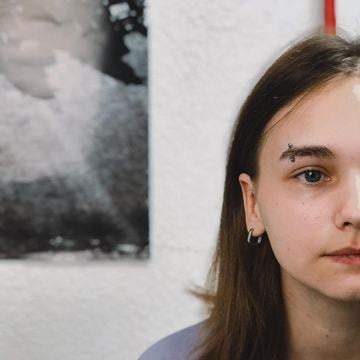 Detail obličeje s vertikálním piercingem ve vnější části obočí (zahnutá činka); ukázka správného umístění a moderního vzhledu.