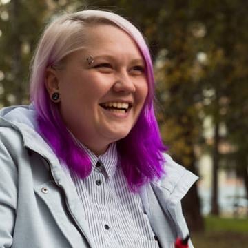 Usmívající se člověk venku s vertikálním piercingem ve vnější části obočí (zahnutá činka); ukázka moderního vzhledu a umístění piercingu obočí.