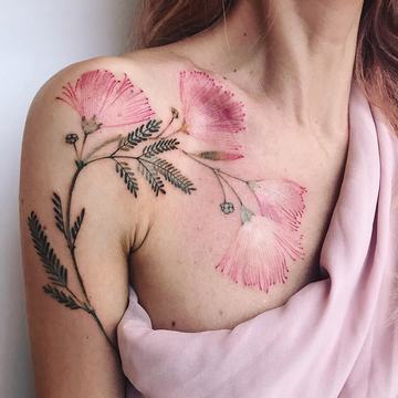 Botanické tetování jemných růžových květů v akvarel/fine line stylu, rozvinuté přes rameno a klíční kost;