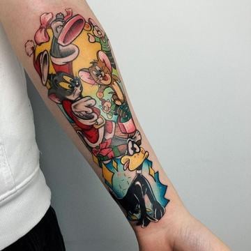 Barevné tetování na vnitřním předloktí: koláž postav z Looney Tunes (Bugs Bunny, Daffy Duck, Tweety a Sylvester) ve výrazném new school stylu se sytými barvami, čistými linkami a vysokým kontrastem – ukázka nápadného tetování na ruku.