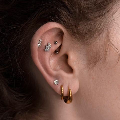 Kombinace několika piercingů vytváří elegantní a vyváženou kompozici. Různé tvary šperků dodávají uchu jemný, osobitý charakter.