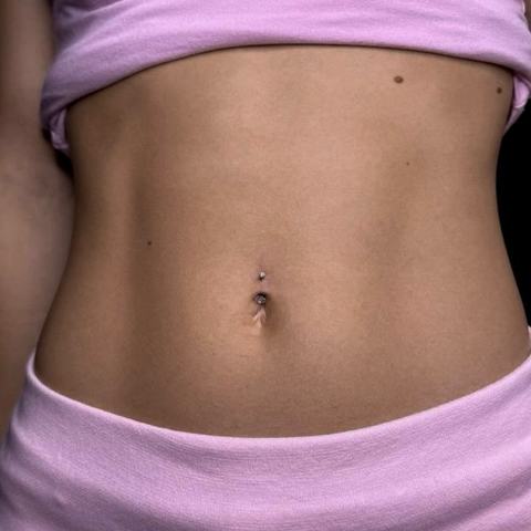 Piercing pupíku působí jemně a elegantně a přirozeně zvýrazňuje linii těla. Decentní šperk dodává celému vzhledu lehký a smyslný akcent.