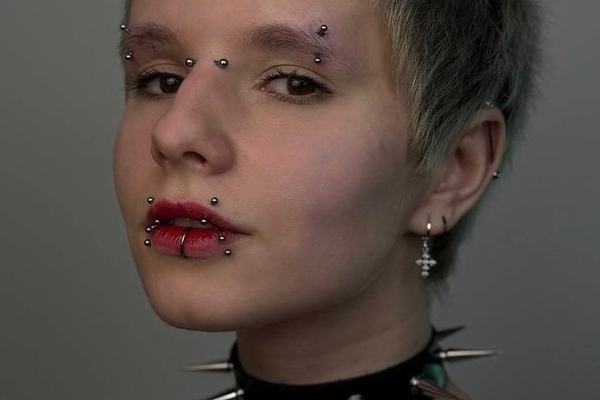 Portrét s krátkým účesem a několika obličejovými piercingy