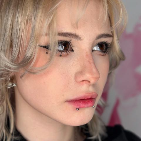 Kombinace jemných piercingů dodává tváři výrazný, lehce alternativní charakter. Stříbrné šperky harmonicky doplňují osobitý vzhled.